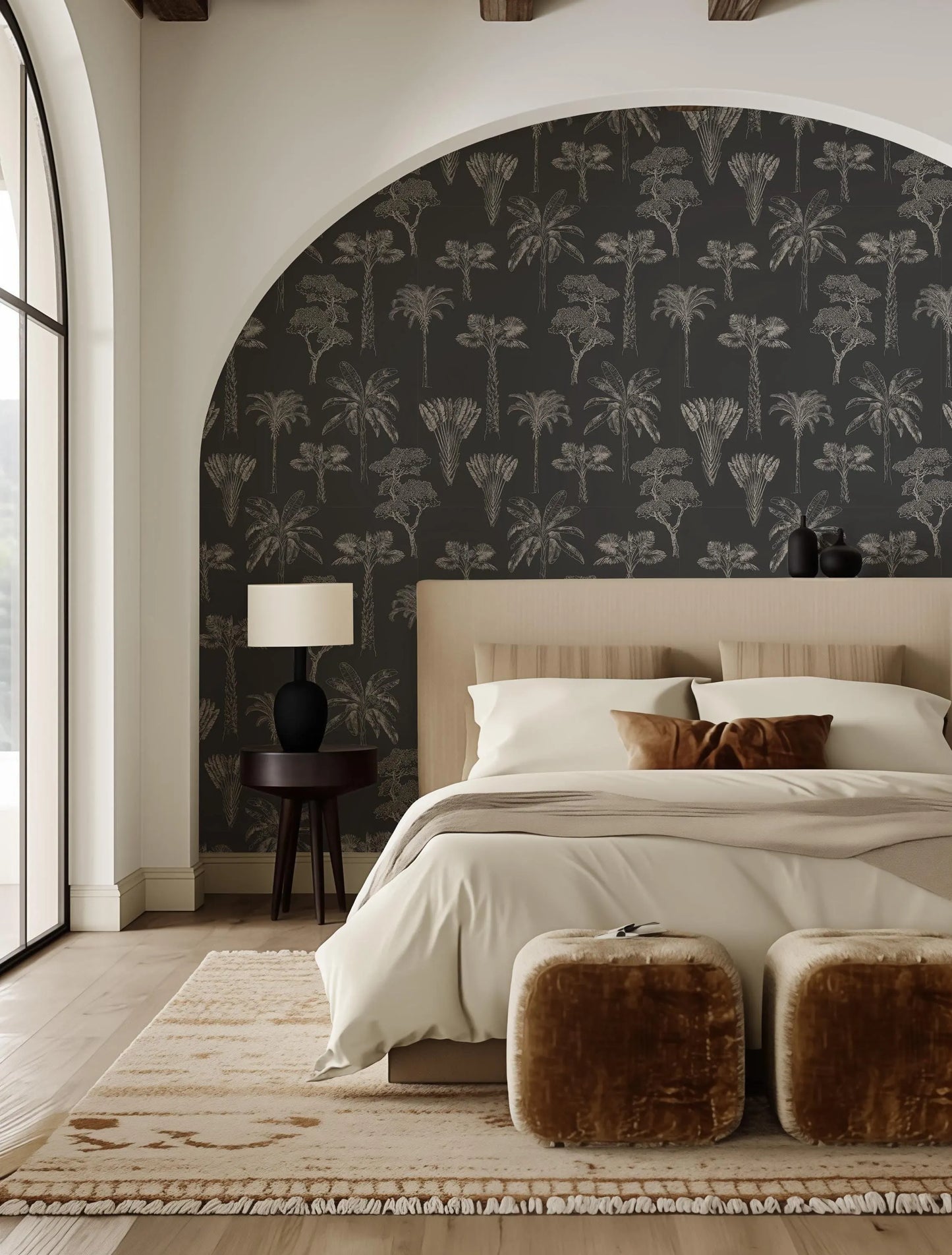 a modern bedroom with a large bed, a wooden headboard, and a black and white patterned wallpaper. The room has a neutral color palette, with a beige bedspread and brown ottomans. The room is well-lit, with a large window providing natural light.