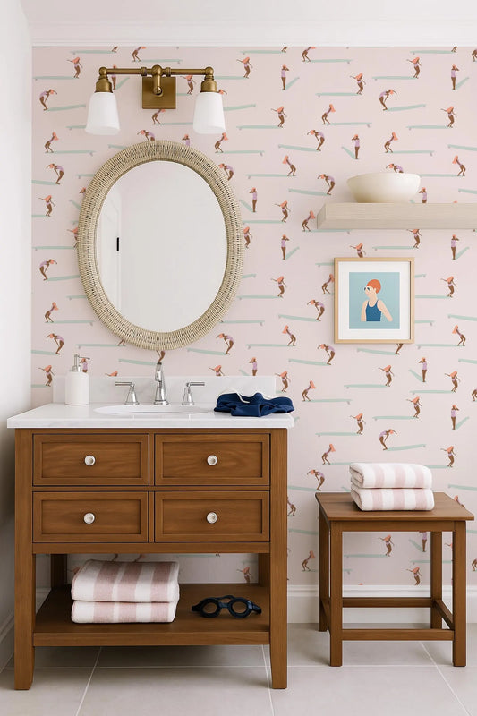 a bathroom with a wooden vanity, a round mirror, and a colorful wallpaper with a pattern of surfers. The bathroom also includes a small table and a stool, as well as a framed picture on the wall.