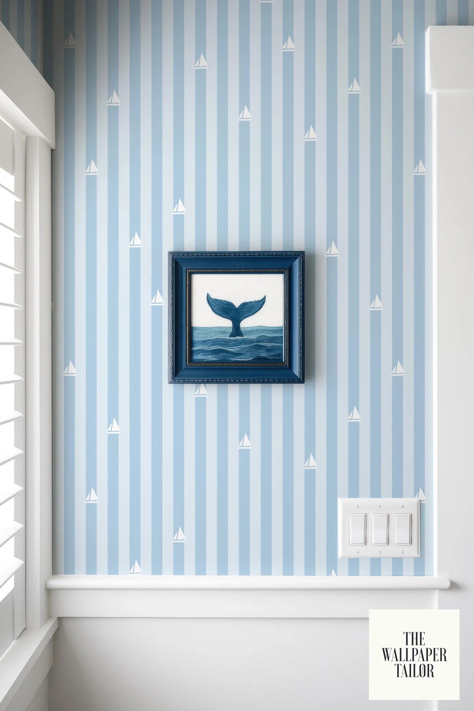 a framed picture of a whale on a wall with blue and white striped wallpaper.