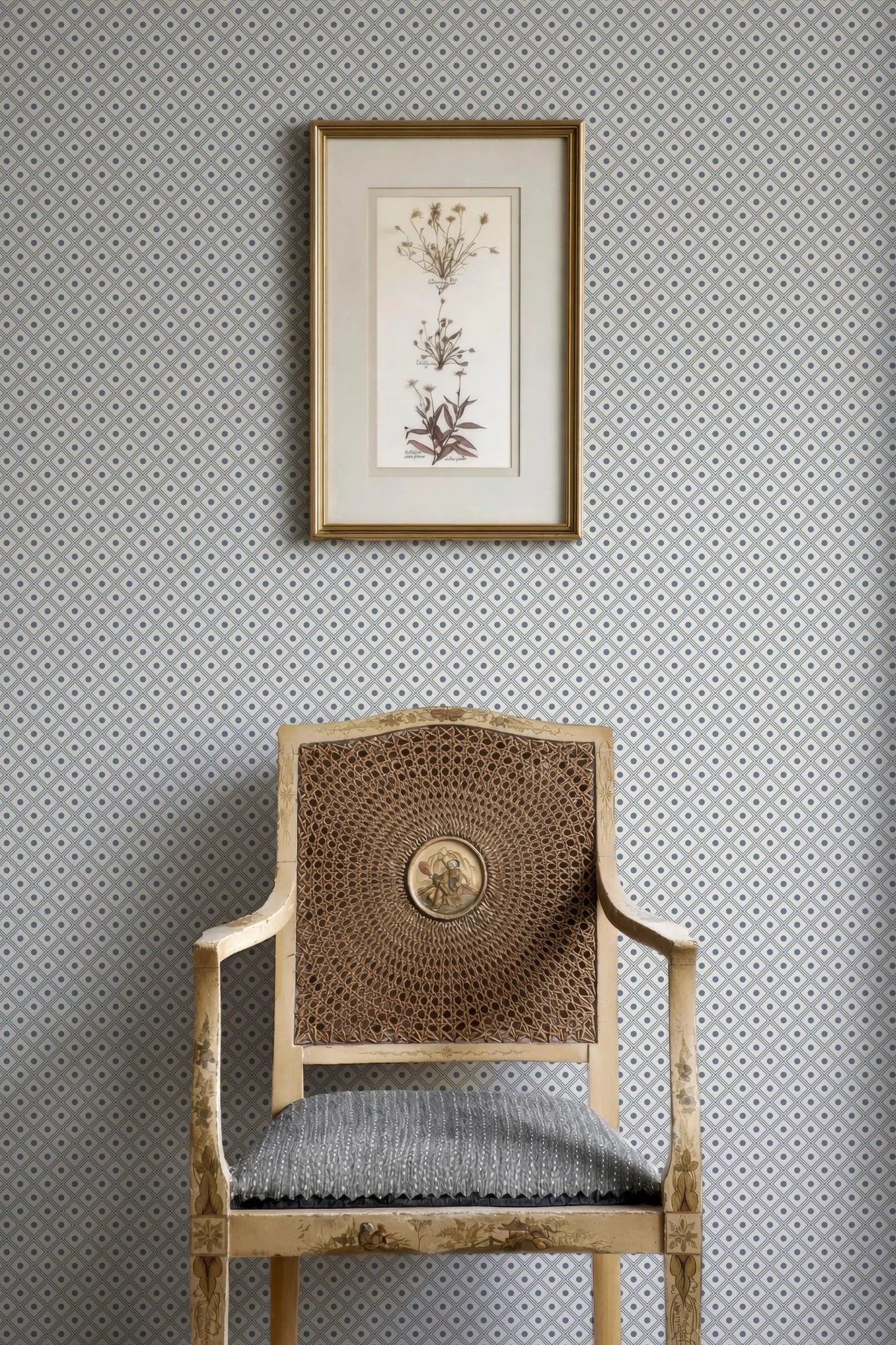 a wooden chair with a woven seat, positioned against a wall with a framed botanical print hanging above it.