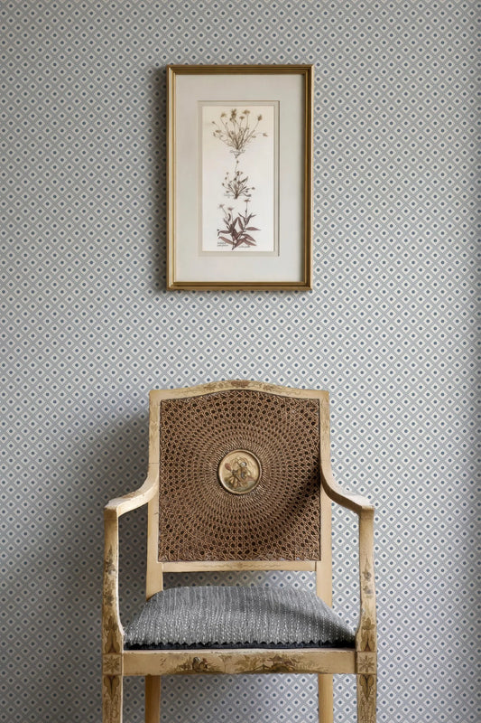 a wooden chair with a woven seat, positioned against a wall with a framed botanical print hanging above it.