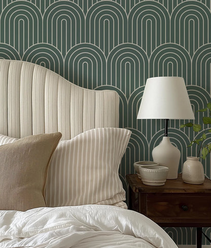 a bedroom with a bed, a nightstand, and a lamp. The bed has a white headboard and a striped pillow. The nightstand has a lamp and a small bowl on it. The wall behind the bed has a repeating pattern of arches in shades of green and white.