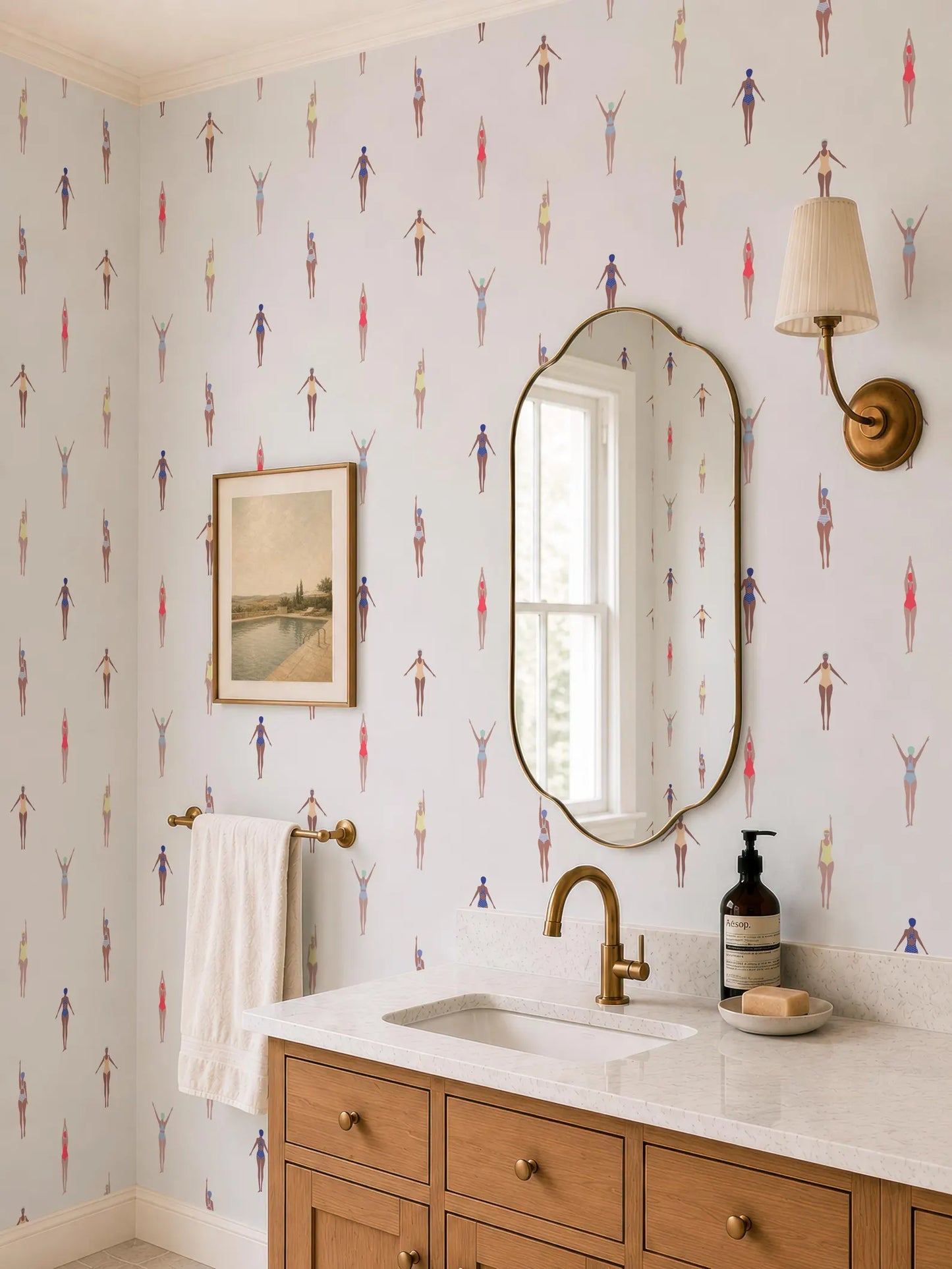 a bathroom with a white sink, a mirror, and a wallpapered wall with a pattern of swimming figures. There is also a wooden vanity with a sink and a bottle of soap on it.