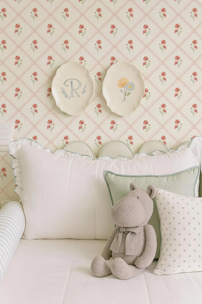 a cozy bedroom scene with a plush teddy bear sitting on a bed, surrounded by decorative pillows and a floral wallpaper.