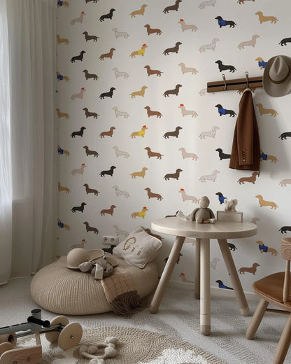 a child's bedroom with a wallpapered wall adorned with a pattern of dachshunds in various colors and sizes. The room includes a small round table, a bean bag chair, and a wooden chair. There is also a hat hanging on the wall and a coat rack nearby.