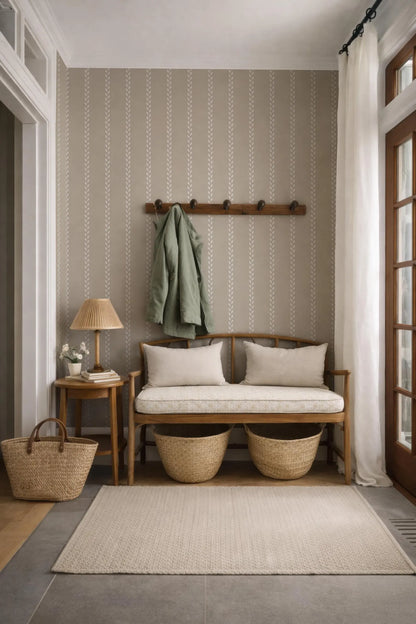 a cozy and inviting entryway with a wooden bench, a woven basket, and a wooden coat rack. The walls are adorned with a striped wallpaper, and a large window with white curtains allows natural light to enter the space.