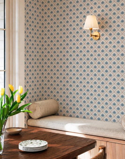 a cozy dining area with a wooden table, a striped bench, and a wallpapered wall with a lamp. A vase of yellow tulips is placed on the table, and there are plates and a bowl on the table.