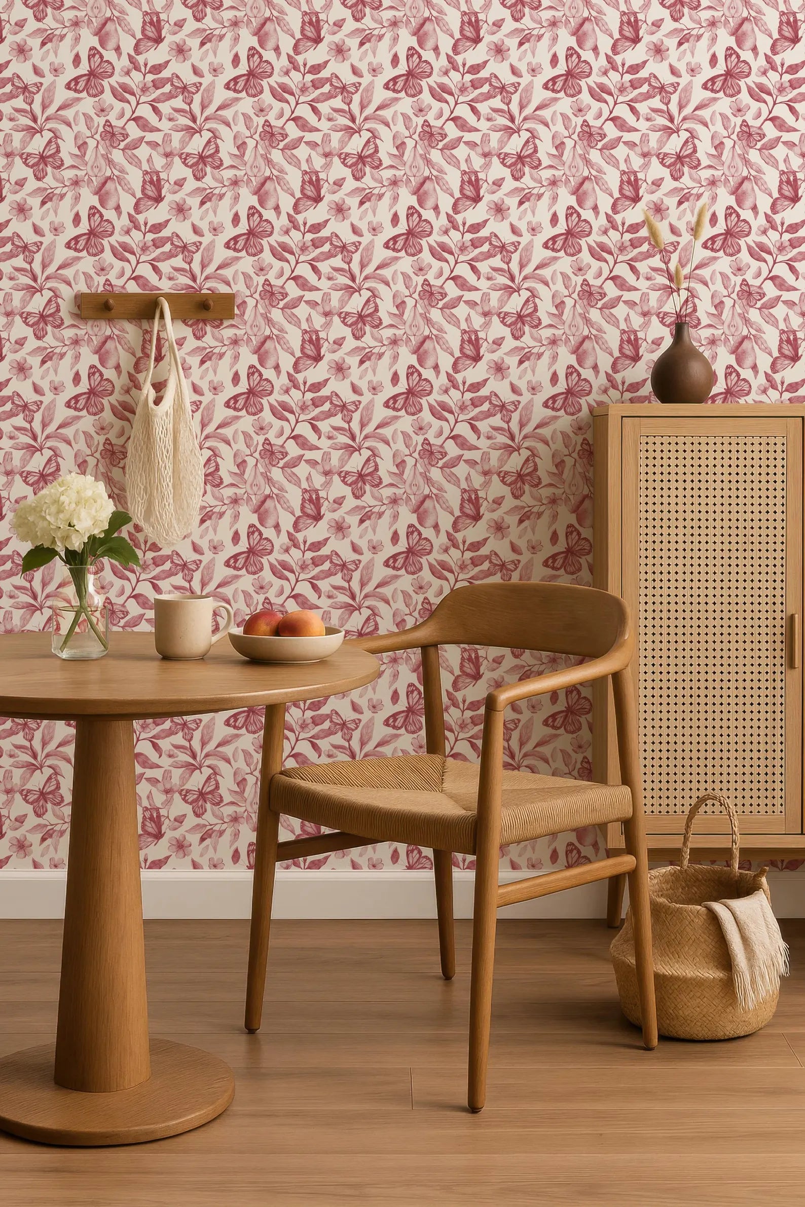 a cozy and inviting dining area with a wooden table, chair, and a woven basket. The table is set with a vase of flowers, a bowl of fruit, and a cup. The chair is positioned next to a wooden cabinet, creating a comfortable and functional space for dining or relaxation.