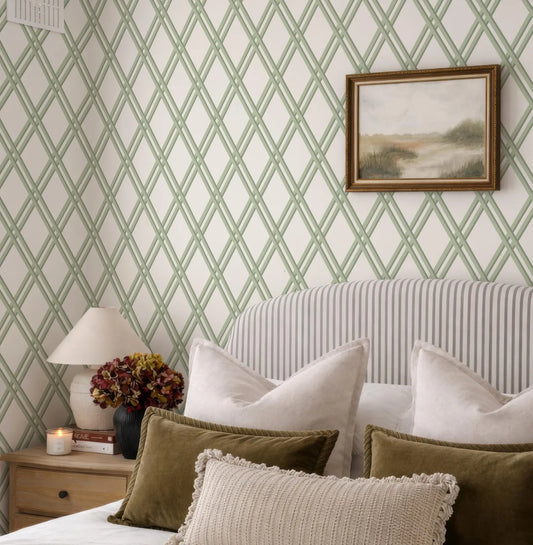 a bedroom with a striped headboard, a framed landscape painting on the wall, and a wooden nightstand with a lamp and a vase of flowers.