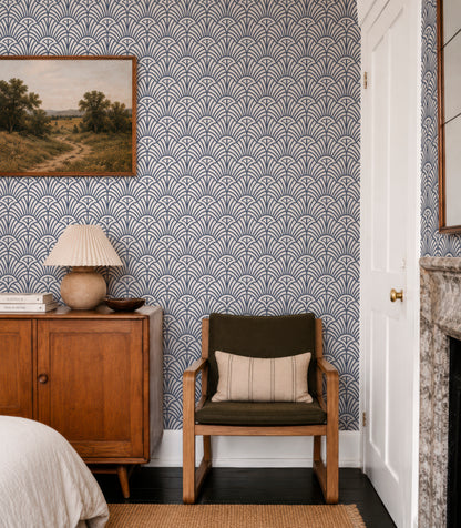 a cozy bedroom with a wooden dresser, a green armchair, and a fireplace. The walls are covered in a patterned wallpaper, and there is a painting hanging above the dresser.