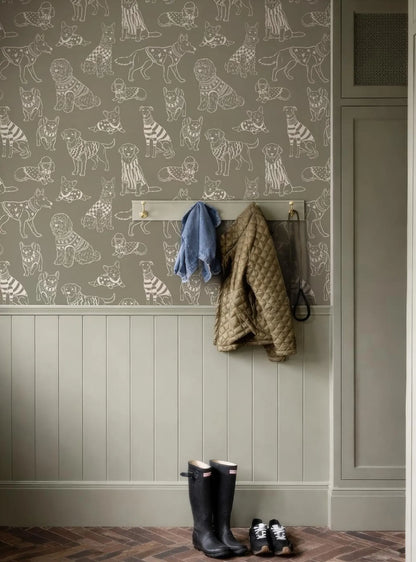a hallway with a wallpapered wall, a coat rack with a jacket and a blue jacket hanging on it, and a pair of black rain boots placed on the floor next to the coat rack.