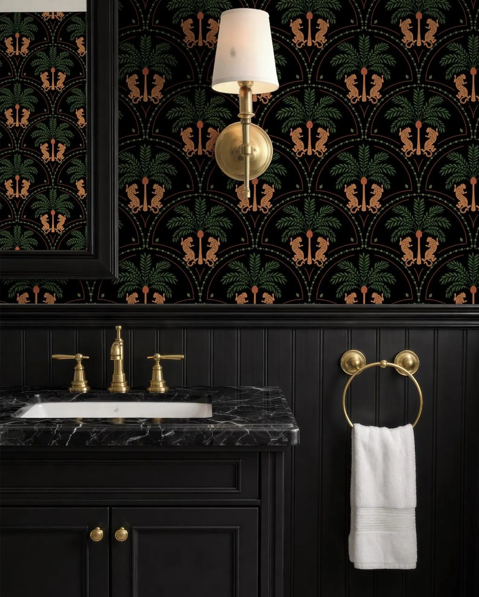 a bathroom with a black vanity, a marble countertop, and a gold faucet. The walls are covered in a black and gold patterned wallpaper, and there is a gold-colored light fixture hanging above the vanity.