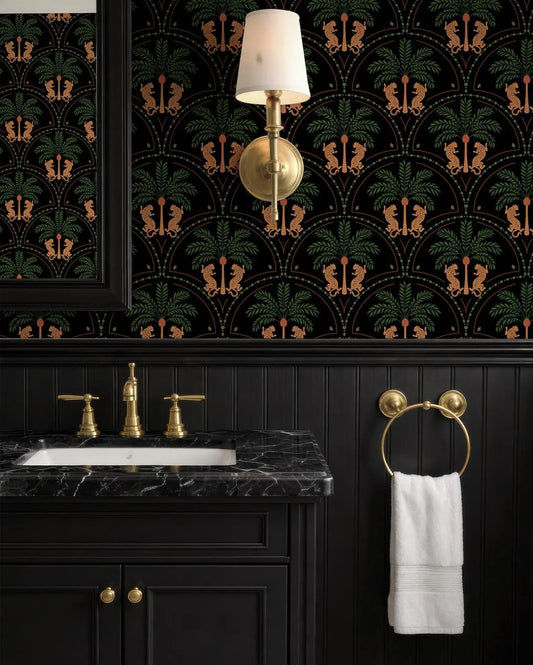 a bathroom with a black vanity, a marble countertop, and a gold faucet. The walls are covered in a black and gold patterned wallpaper, and there is a gold-colored light fixture hanging above the vanity.