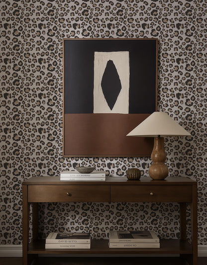 a wooden console table with a lamp, books, and a framed abstract artwork on a leopard print wallpaper.