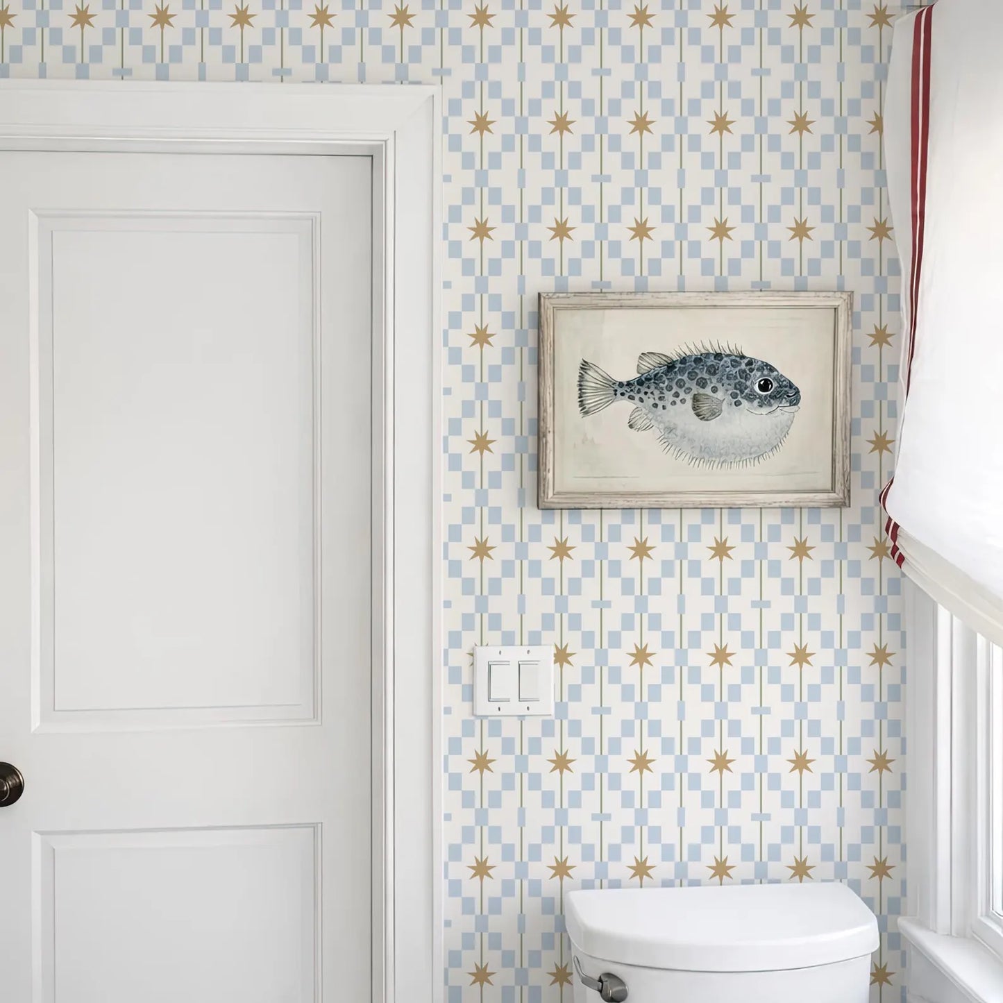 a bathroom with a white door, a framed picture of a fish on the wall, and a white toilet.
