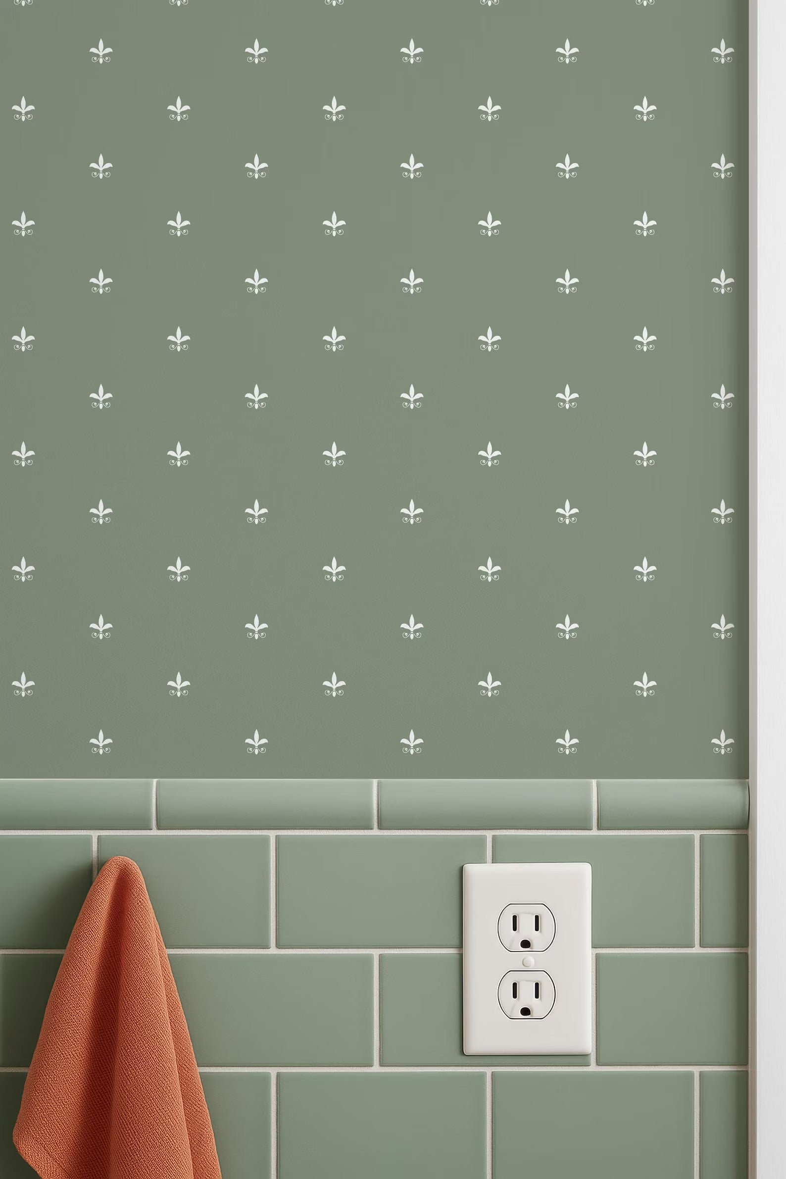 a wall with a green tile pattern and a white electrical outlet on the wall. There is also a red towel hanging on the wall.