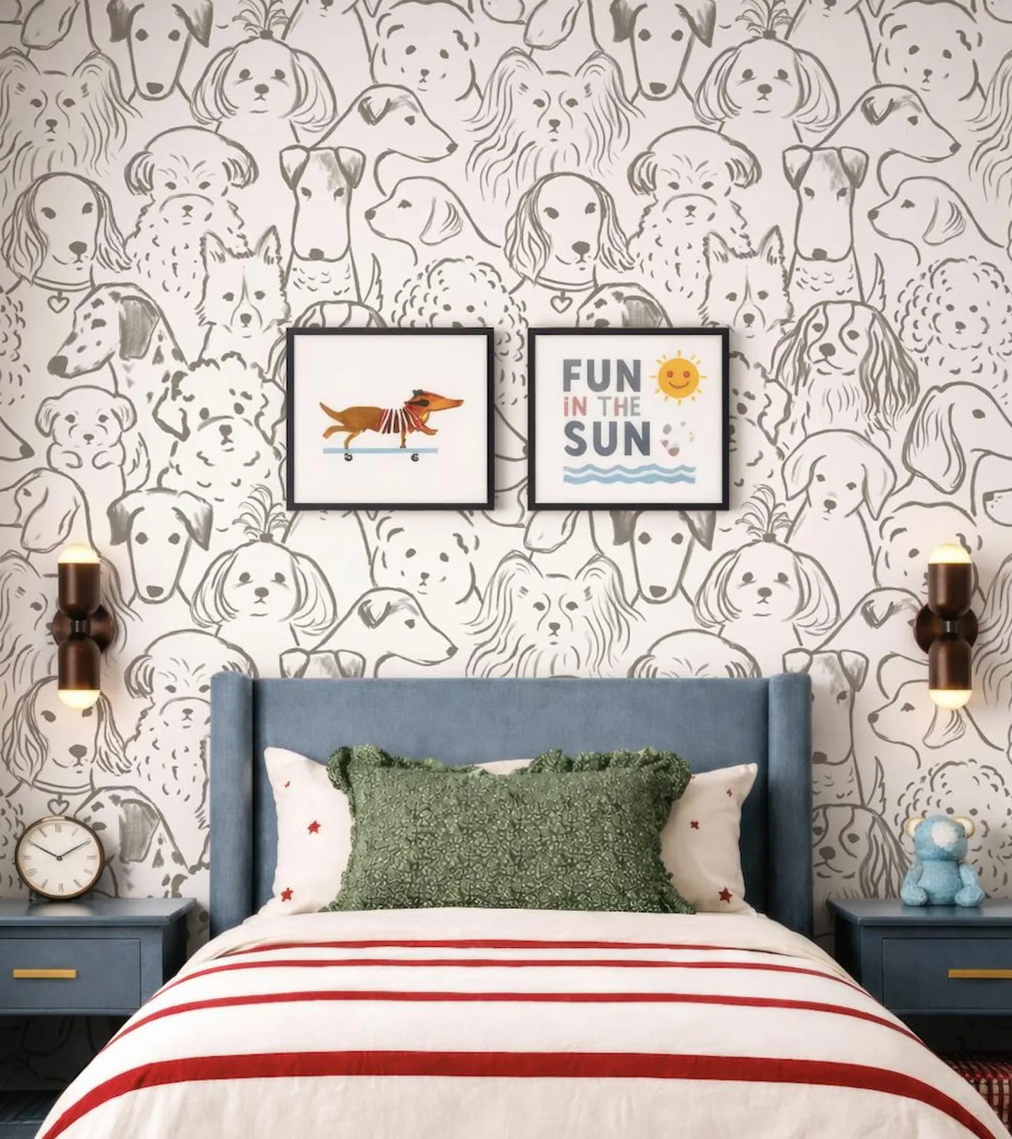 a bedroom with a bed, two nightstands, and a wallpapered wall with a repeating pattern of dog faces. Above the bed, there are two framed pictures of dogs. The wall also has a playful message that reads "Fun in the Sun".