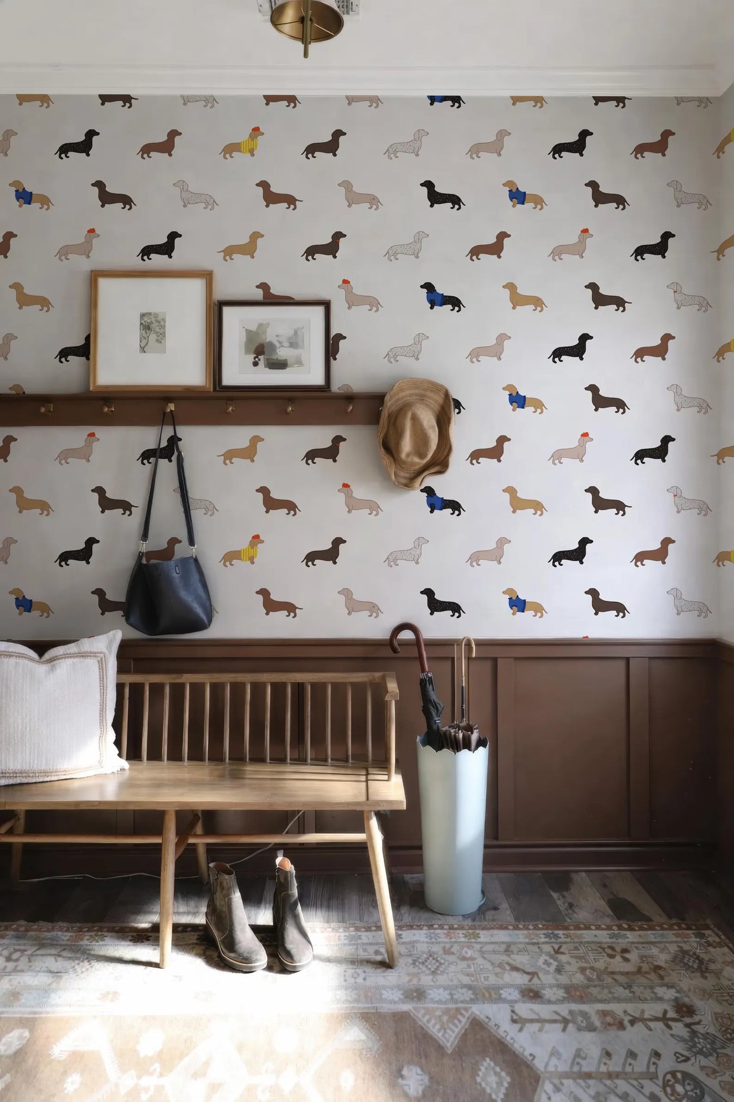 a room with a wallpapered wall adorned with a pattern of dachshunds in various shades of brown and black. The room also contains a wooden bench, a hat rack, and a pair of boots.