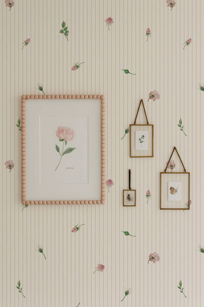 a wallpapered wall with a framed picture, two framed pictures, and a framed picture hanging on it. The wallpapered wall has a floral pattern, and the framed pictures and picture frame are also adorned with a floral pattern.