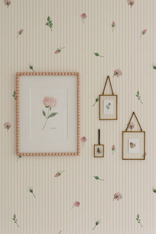 a wallpapered wall with a framed picture, two framed pictures, and a framed picture hanging on it. The wallpapered wall has a floral pattern, and the framed pictures and picture frame are also adorned with a floral pattern.