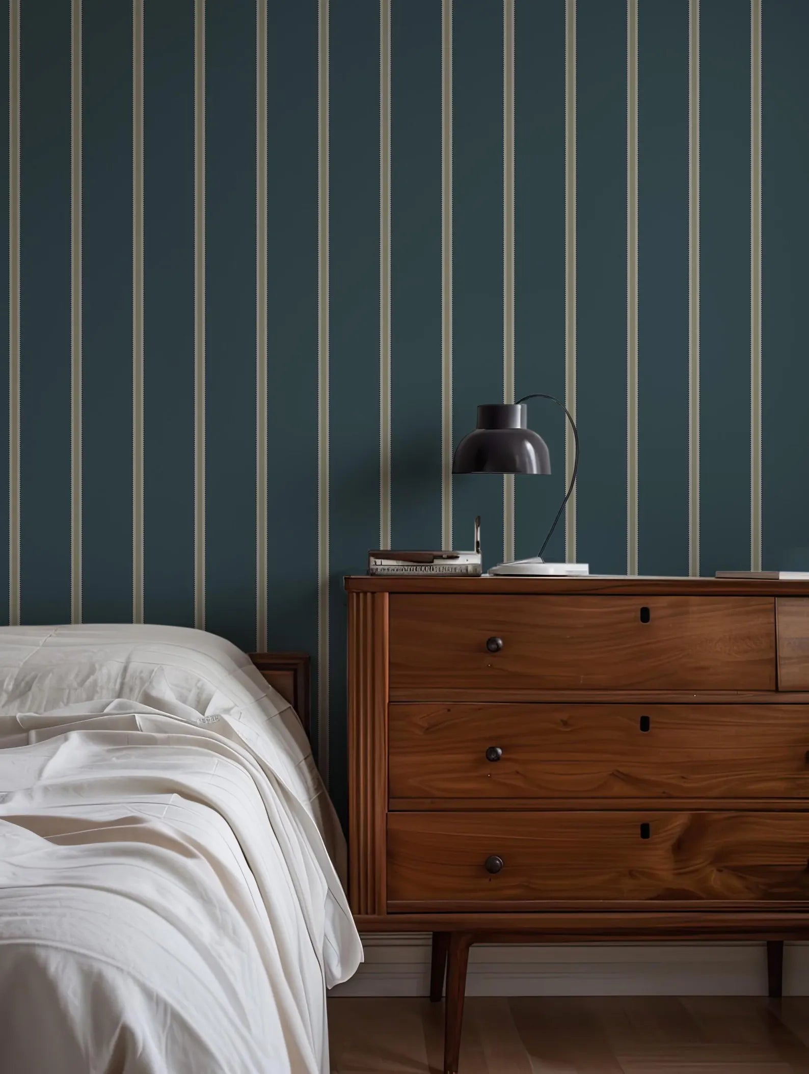 a bedroom with a bed, a wooden dresser, and a striped wallpaper.