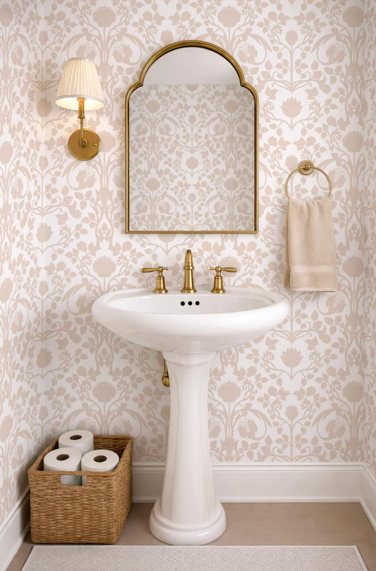 a bathroom with a white pedestal sink, a mirror above it, and a towel rack on the wall. The walls are covered in a patterned wallpaper, and there is a basket of toilet paper on the floor next to the sink.