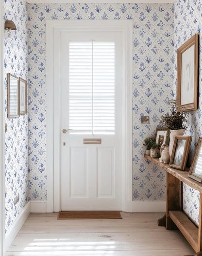 a hallway with a white door, a wooden console table with framed pictures, and a blue and white patterned wallpaper.