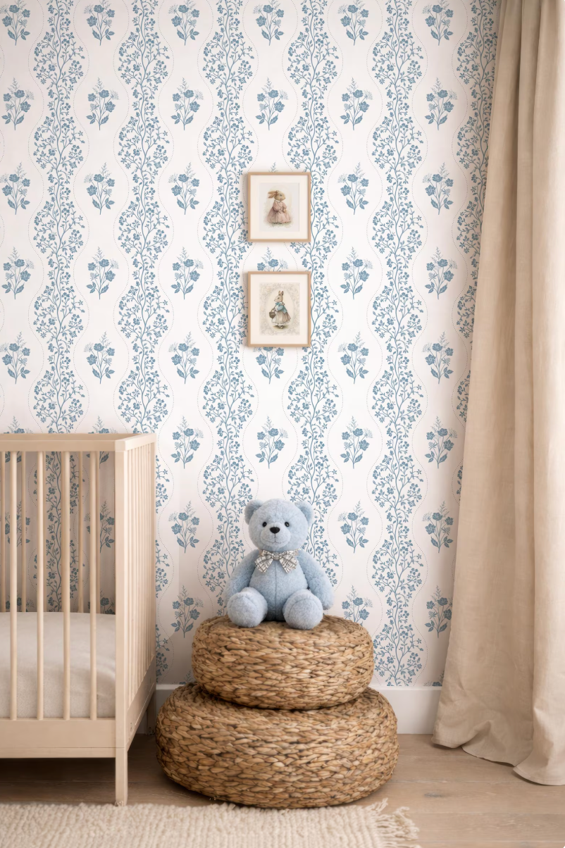 a nursery room with a wooden crib, a blue teddy bear sitting on a woven basket, and a floral wallpaper.