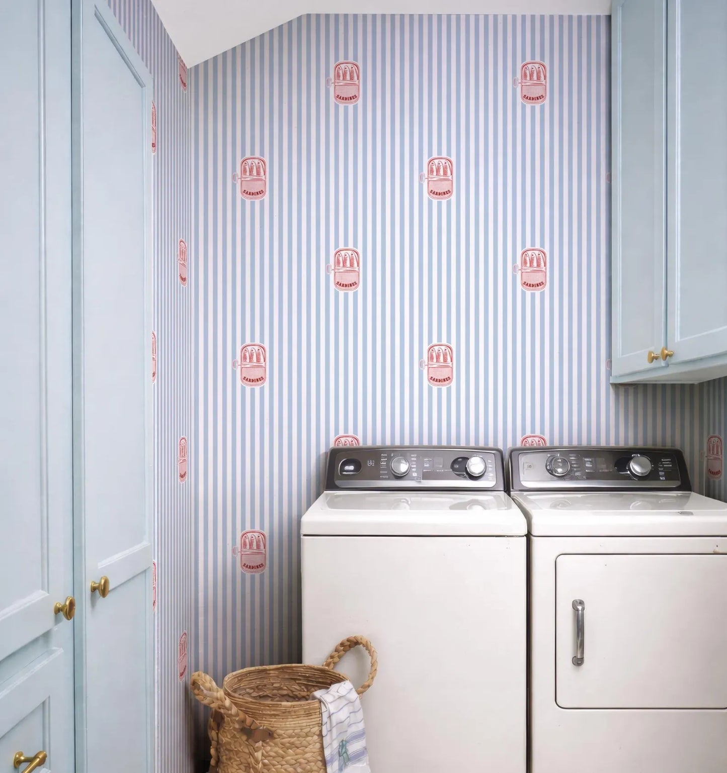 a laundry room with two washing machines and a basket of laundry. The walls are decorated with a striped wallpaper featuring a repeating pattern of red and white icons.