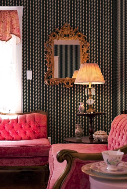 a cozy and elegant living room with a pink tufted sofa, a wooden side table with a lamp, and a large ornate mirror on the wall.