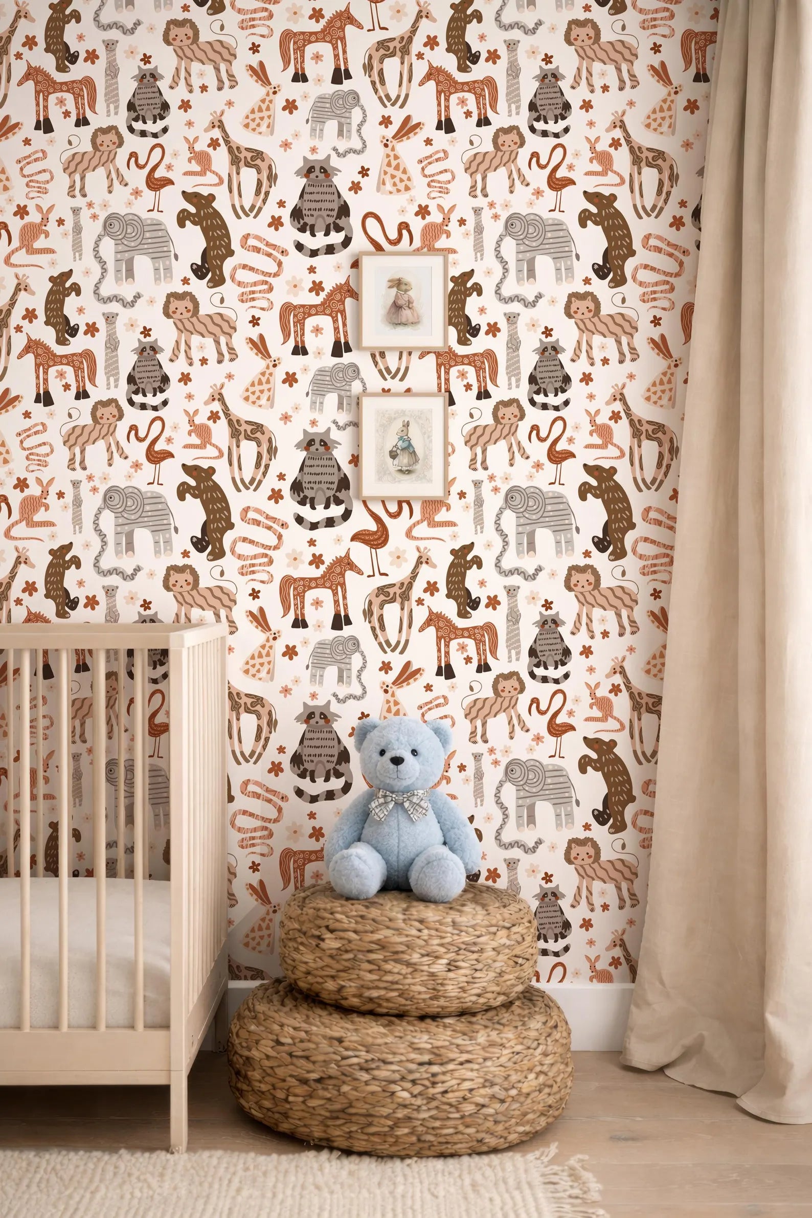 A nursery room with a wooden crib, a stack of woven baskets, and a blue teddy bear. The walls are covered in a patterned wallpaper featuring various animals and wildlife.