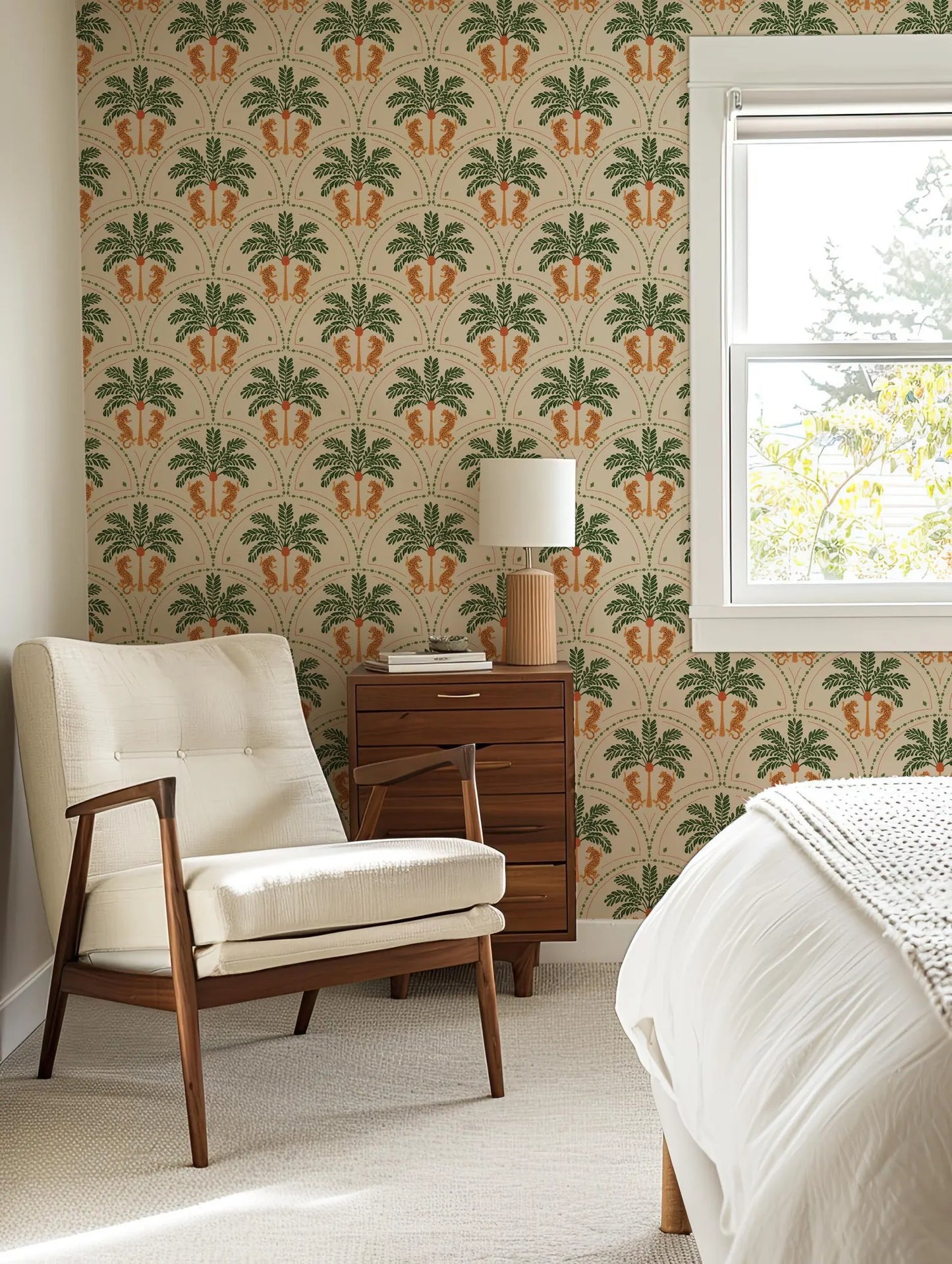 a cozy bedroom with a white armchair, a wooden side table, and a window with a view of trees outside. The room has a tropical theme, with a patterned wallpaper and a white color scheme.