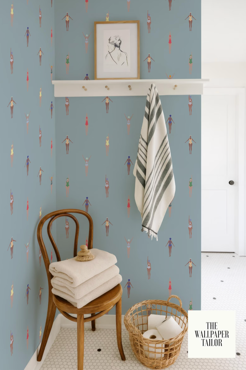 a bathroom with a blue and white color scheme, a wooden chair with folded towels, a towel rack with a striped towel, and a basket of toilet paper.