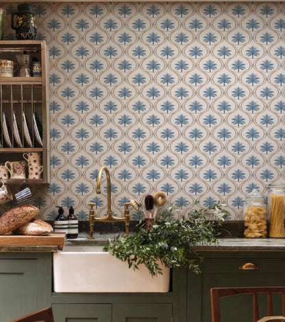 a kitchen with a sink, a wooden shelf with dishes, and a wall with a patterned wallpaper. The kitchen has a rustic and cozy atmosphere, with a mix of natural and vintage elements.