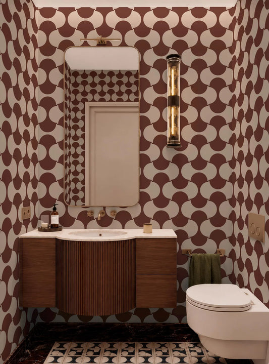 a bathroom with a white sink, a mirror, and a toilet. The walls are covered in a patterned wallpaper with a repeating design of circles and lines in shades of brown and white.