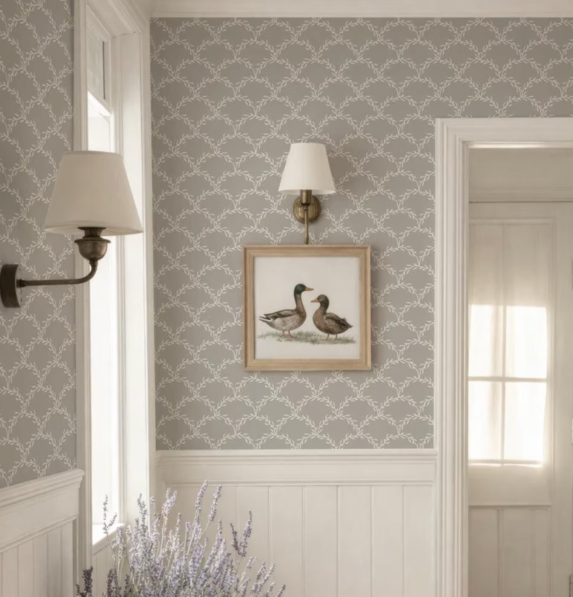 a room with a gray and white patterned wallpaper, a framed picture of two ducks, and two wall sconces.