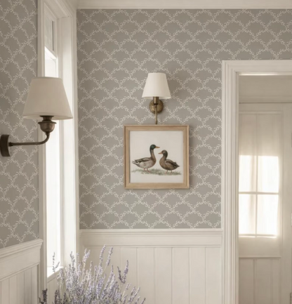a room with a gray and white patterned wallpaper, a framed picture of two ducks, and two wall sconces.