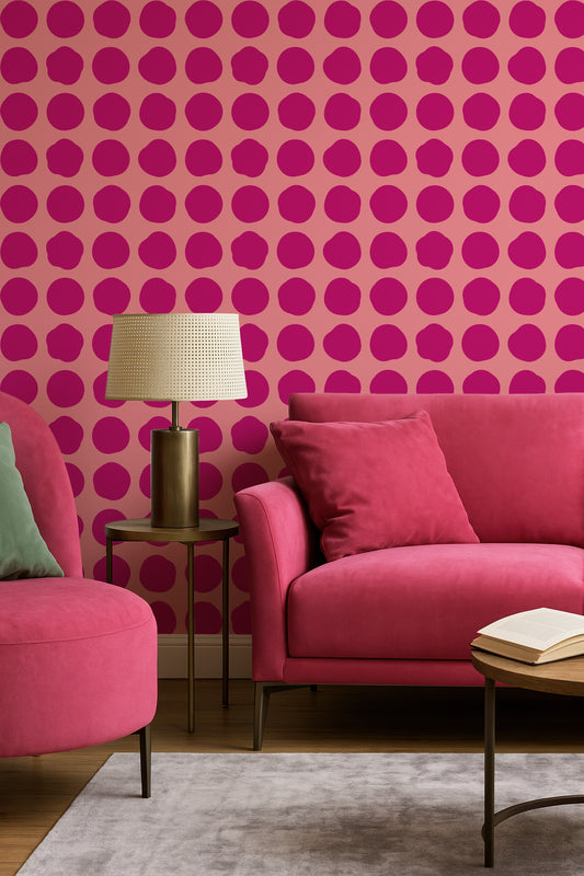 a living room with a pink sofa, a round table with a lamp, and a green armchair. The walls are covered in a pattern of pink circles, creating a vibrant and lively atmosphere.