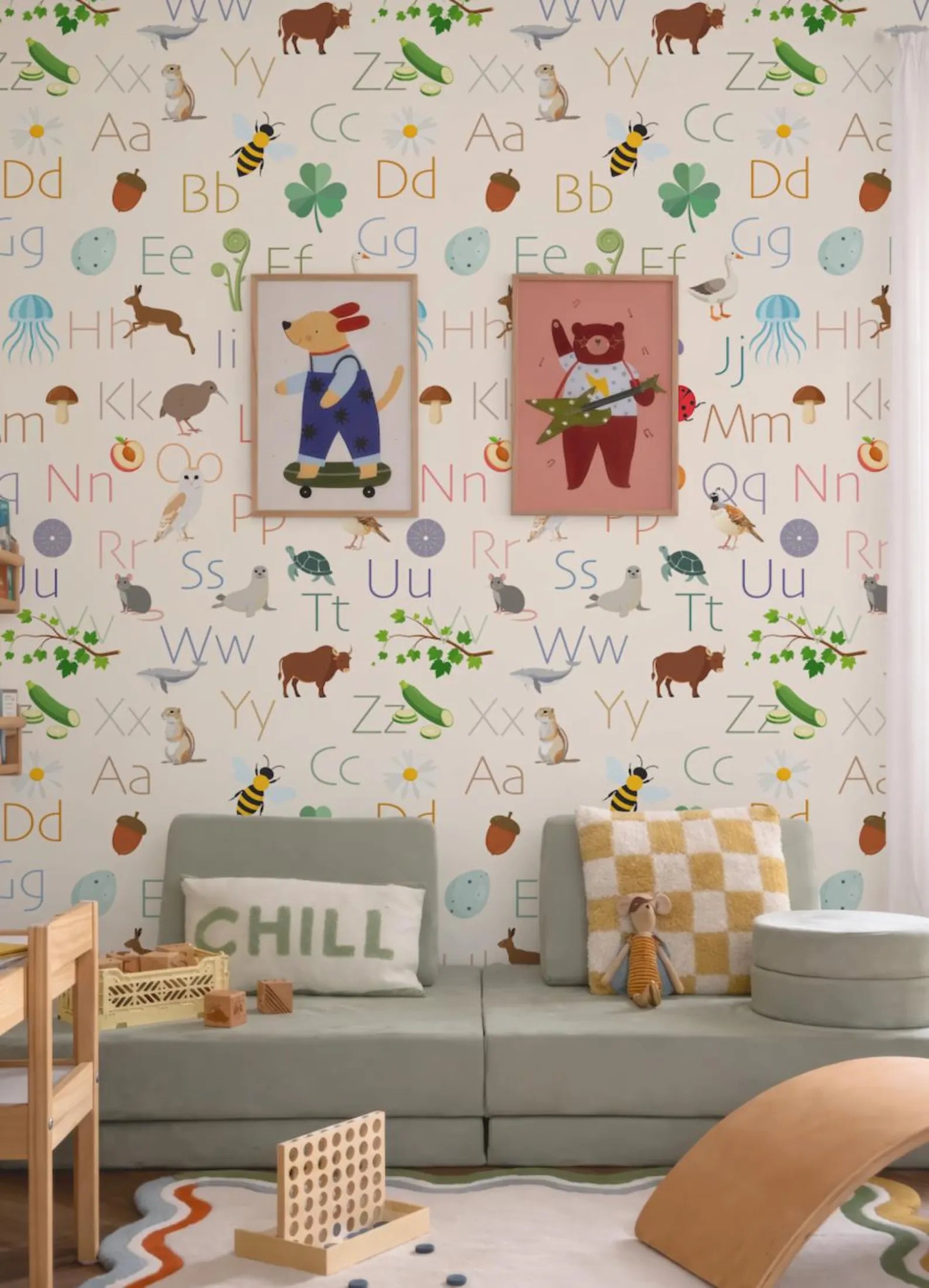 a colorful and playful children's room with a wallpapered wall that displays the alphabet in a variety of vibrant colors and playful animal illustrations. The room includes a couch, a chair, and a toy chest, creating a cozy and inviting atmosphere for a child's play area.
