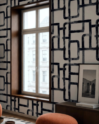 a modern interior design with a large window, a black and white geometric pattern on the wall, and a framed photograph on a wooden shelf.