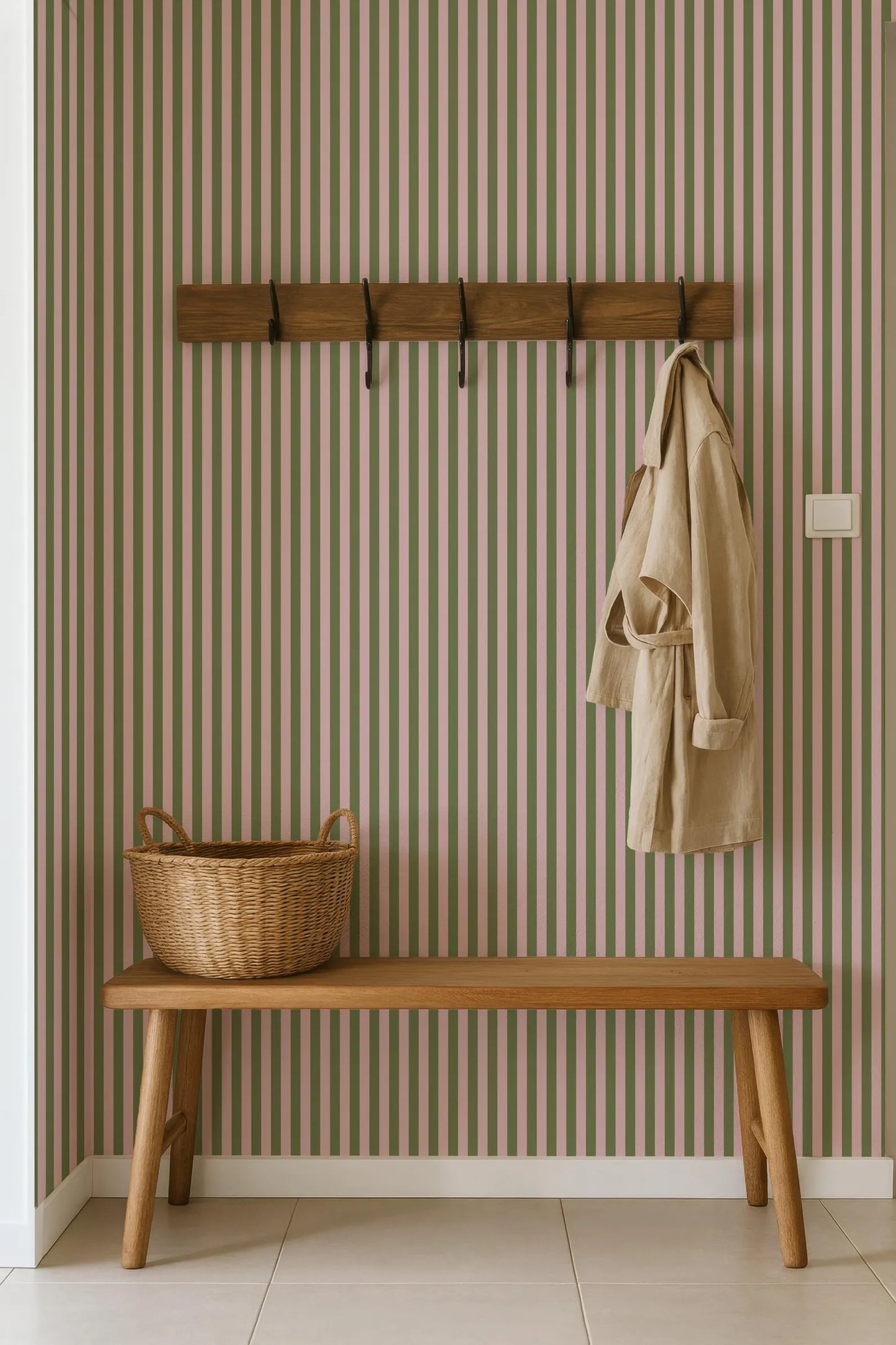 a wooden bench with a wicker basket on it, placed against a striped wall with a coat rack above it.