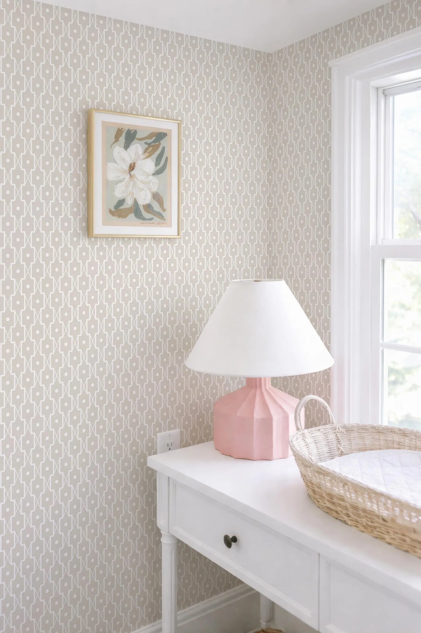 a white dresser with a pink lamp and a woven basket on top, situated next to a window.