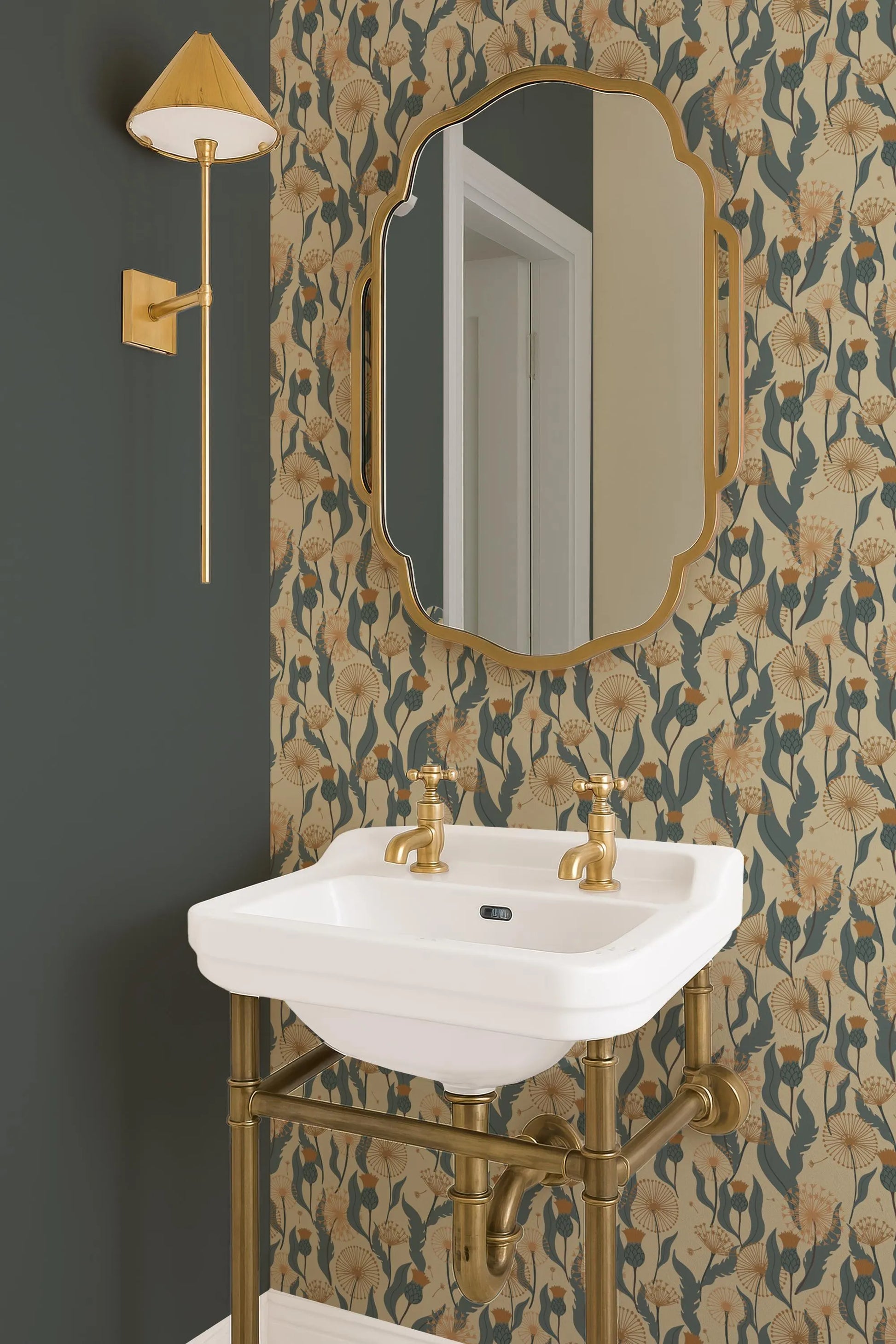 a bathroom with a white sink, a gold-framed mirror, and a gold-colored light fixture. The walls are adorned with a floral wallpaper pattern in shades of green and gold.