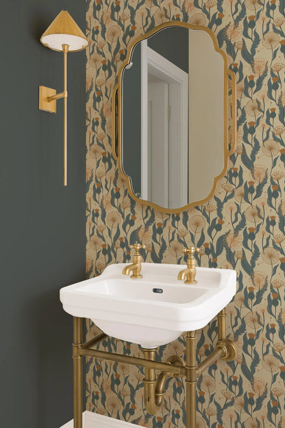 a bathroom with a white sink, a gold-framed mirror, and a gold-colored light fixture. The walls are adorned with a floral wallpaper pattern in shades of green and gold.