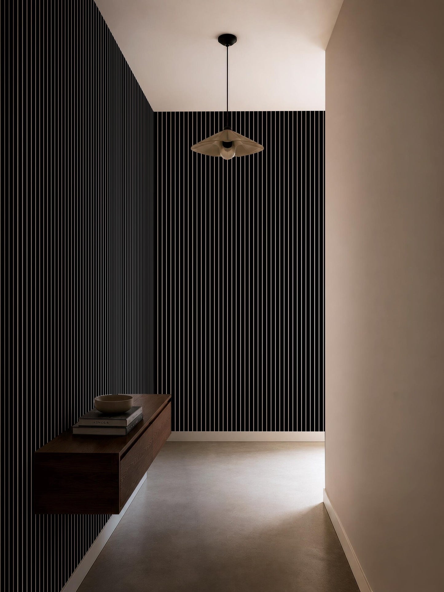 a minimalist hallway with a black and white striped wall, a wooden shelf, and a hanging light fixture.