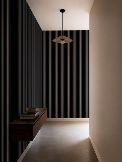 a minimalist hallway with a black and white striped wall, a wooden shelf, and a hanging light fixture.