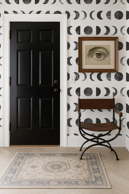 a black door, a brown chair, and a framed artwork on a wall with a black and white pattern.