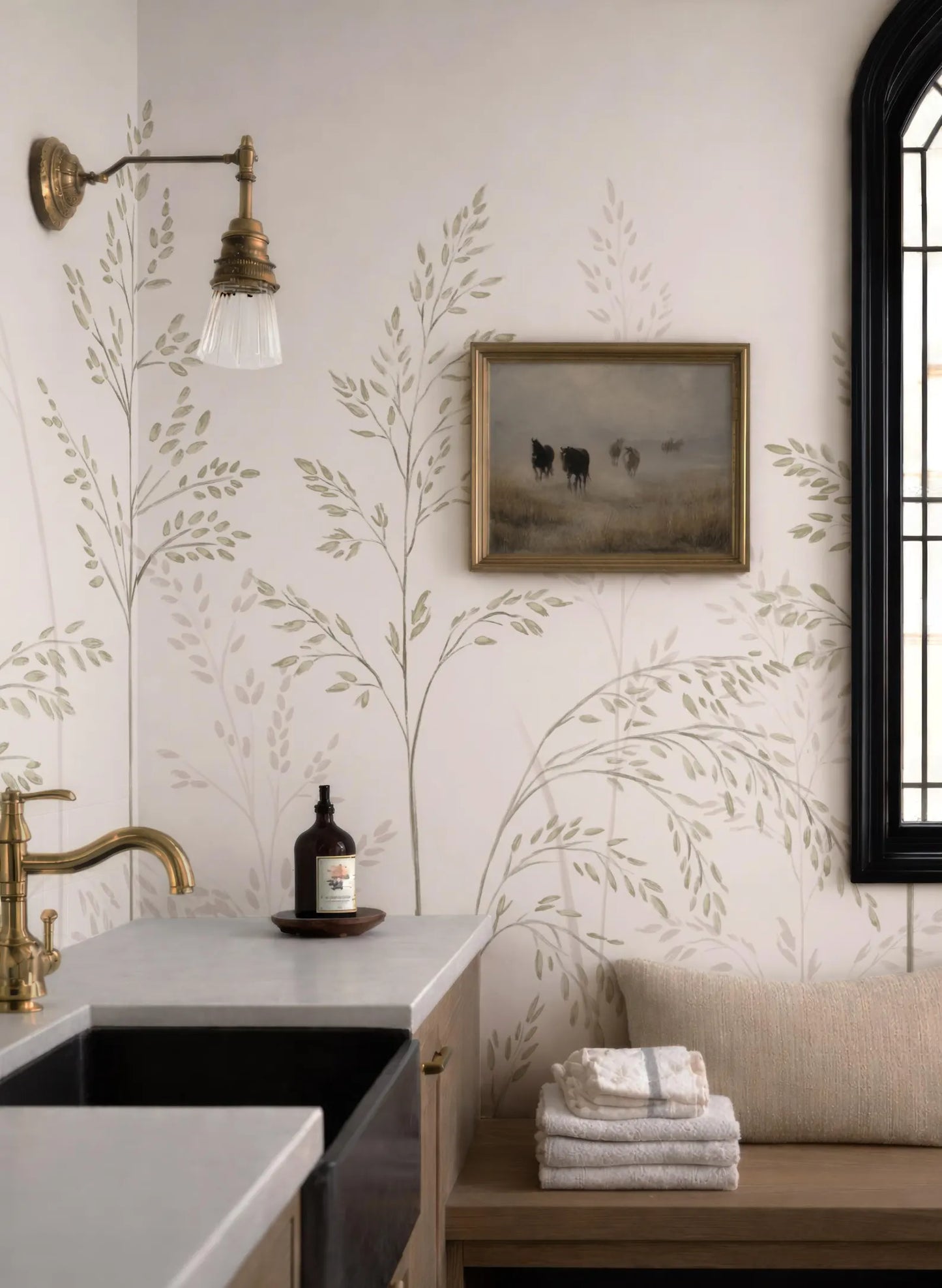 a bathroom with a sink, a framed painting of cows on the wall, and a decorative plant on the wall.