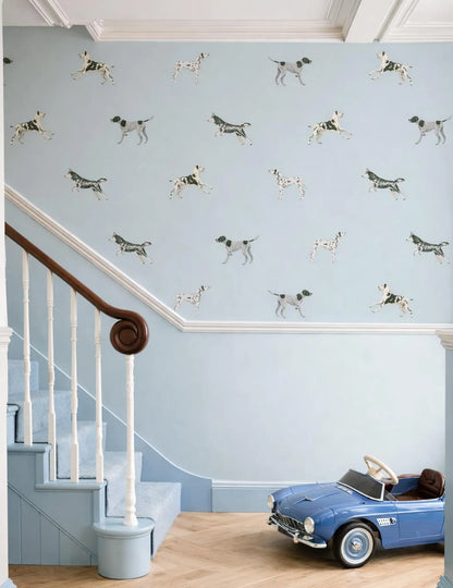 a blue staircase with a pattern of black and white dogs on the wall behind it, and a blue toy car is parked on the floor next to the stairs.