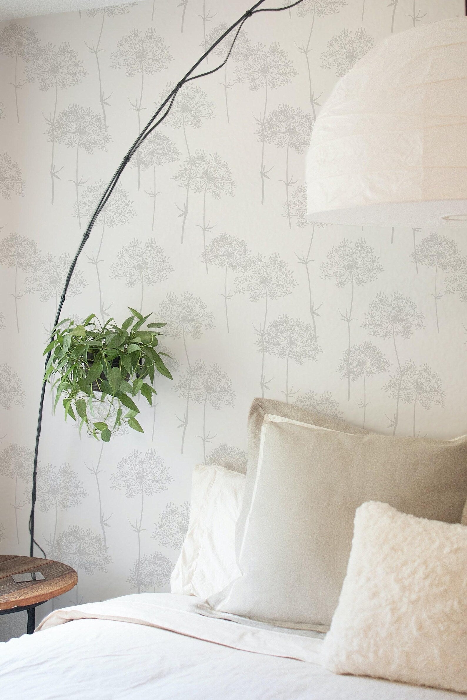 a cozy bedroom scene with a bed adorned with white pillows and a green plant hanging from the wall. The wall is decorated with a repeating pattern of gray trees, creating a serene and calming atmosphere. A lamp is also present in the room, providing soft lighting.